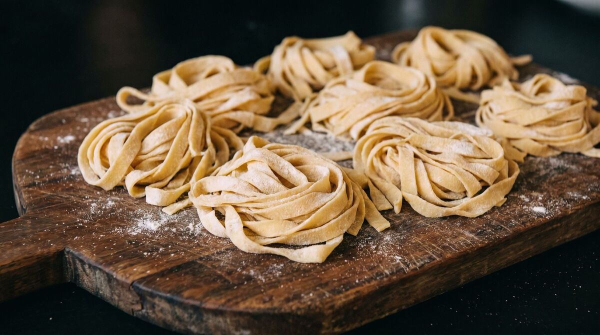 Hnízda čerstvých tagliatelle na pomoučeném prkénku